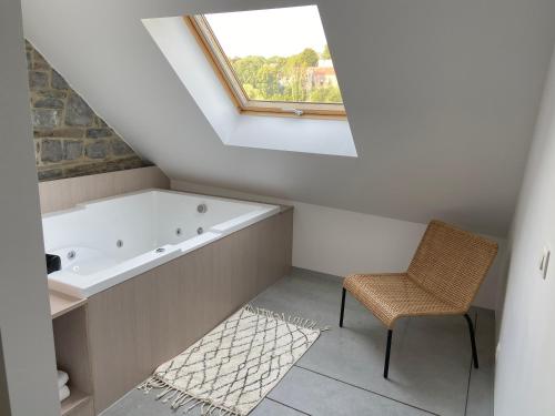 a bathroom with a bath tub and a chair at Fenêtre sur Theux in Theux