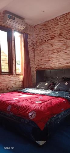 a bedroom with a bed with a red blanket at Vila Kota Bunga Private Pool in Puncak