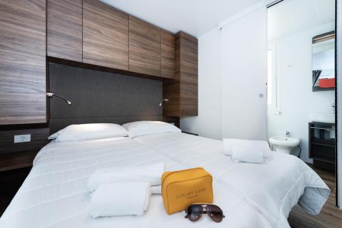 a bedroom with a large white bed with a yellow bag on it at Luxury Camp at Union Lido in Cavallino-Treporti