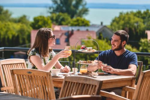 mężczyzna i kobieta siedzący przy stole z kieliszkami do wina w obiekcie Domaine Edegger - Organic Winery Badacsony w mieście Badacsonytomaj