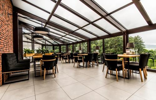 a conservatory with tables and chairs and windows at Hotel Kompleks Beskid z basenem i stokiem narciarskim - blisko Babiej Góry in Spytkowice