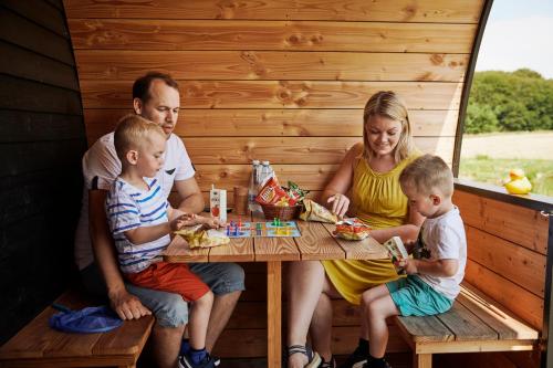 una familia sentada en una mesa en una sauna en Naturhytter, en Kjellerup