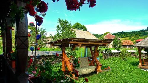 a wooden gazebo with a chair in a garden at Pensiunea Inima Maramureșului in Breb