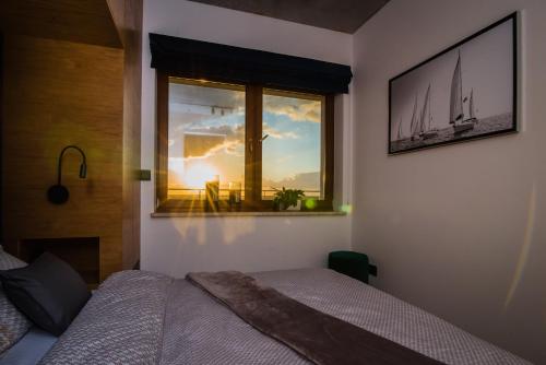 Un dormitorio con una cama y una ventana con un velero. en Apartament WIDOK en Olsztyn
