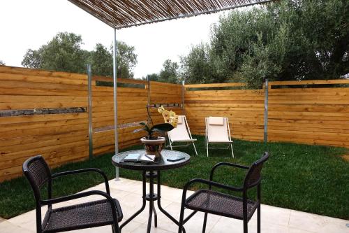 a patio with four chairs and a table with an umbrella at giardino del tempo in Merine
