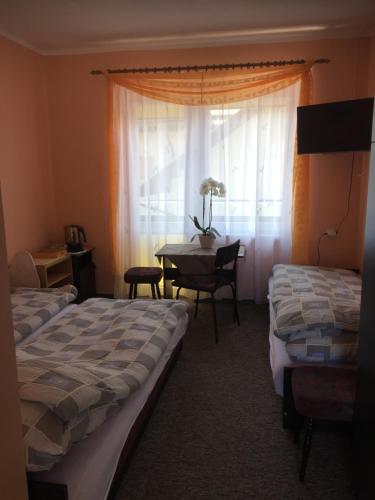 a room with two beds and a table with a window at Pensjonat ''TRYTON'' in Karwia