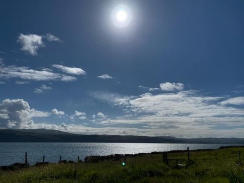 a large body of water with the sun in the sky at White Watch in Lochaline