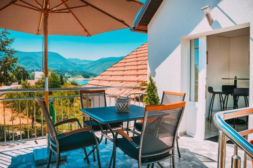 a table and chairs on a balcony with a view at Apartmani Markešić Ramsko jezero in Prozor