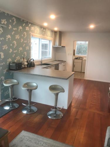 a kitchen with a counter and two bar stools at ROTORUA EASTSIDE APARTMENTS in Rotorua