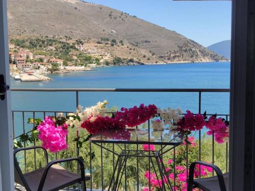 una mesa con flores en un balcón con vistas al agua en Ballas Apartments en Ayia Evfimia