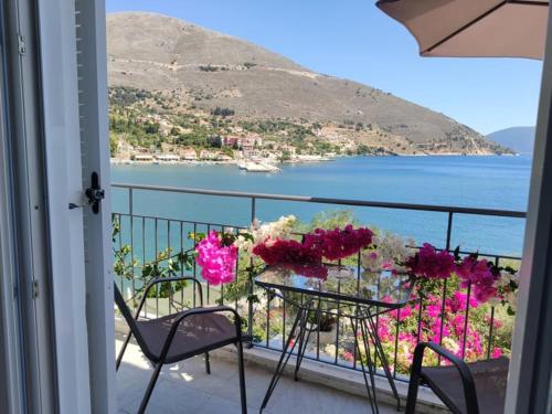 a table and chairs on a balcony with a view of the water at Ballas Apartments in Ayia Evfimia