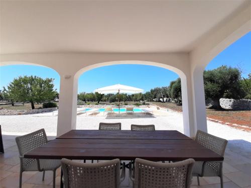 een tafel met stoelen en uitzicht op een zwembad bij Trullo Tranquillo Ostuni in Ostuni