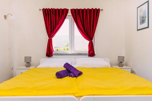 a bedroom with a yellow bed with a window at Apartmani Markešić Ramsko jezero in Prozor