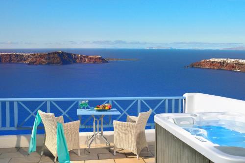 a patio area with chairs and a table with a view of the ocean at Absolute Bliss in Imerovigli