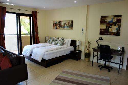 a bedroom with a bed and a desk and a couch at Casa Cataleya Bohol Self-service Apartments in Panglao