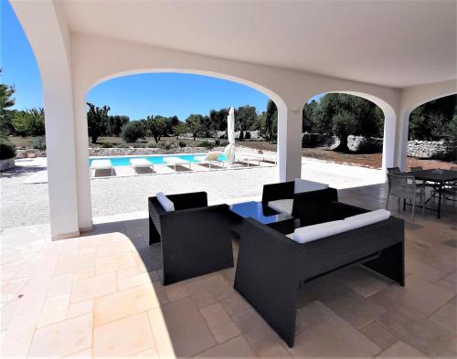 een terras met stoelen en een tafel en een zwembad bij Trullo Tranquillo Ostuni in Ostuni