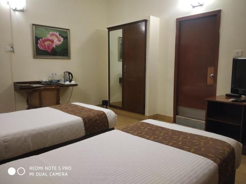 a hotel room with two beds and a television at Hanu Reddy Residences Wallace Garden in Chennai