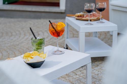 two white tables with two glasses of wine and snacks at Hotel Marinaro in Santa Teresa Gallura