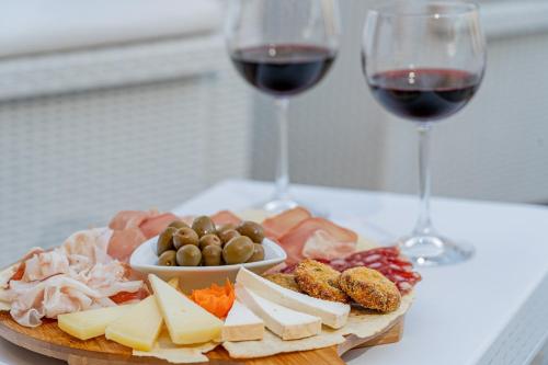 a plate of cheese and meat and two glasses of wine at Hotel Marinaro in Santa Teresa Gallura