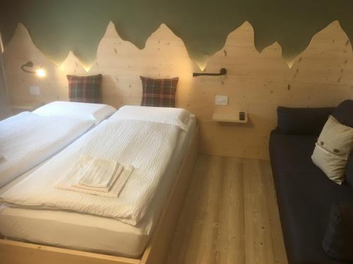 two twin beds in a room with a couch at B and B nonna Rosa vista Lagorai in Capriana