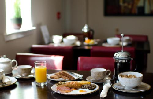 a table topped with plates of breakfast foods and orange juice at The Park Guest House in Aviemore