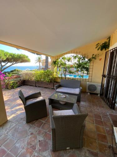 d'une terrasse avec des chaises et des tables et une vue sur l'océan. dans l'établissement Villa Les Glycines, aux Issambres