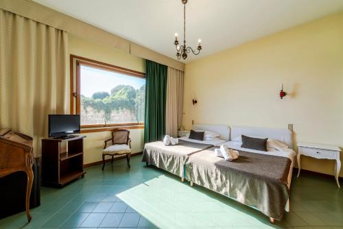 a bedroom with two beds and a television and a window at Hotel Ristorante Maga Circe in San Felice Circeo
