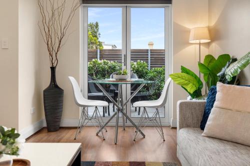 a living room with a glass table and white chairs at The Banq Apartments by Urban Rest in Sydney