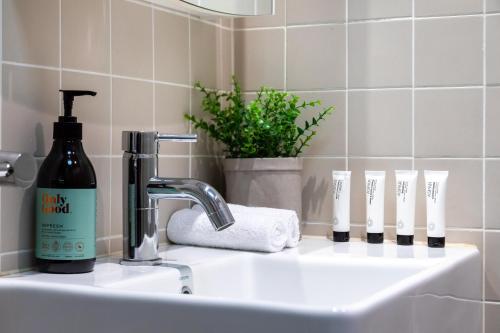 a bathroom sink with a bottle of soap and toothbrushes at The Banq Apartments by Urban Rest in Sydney