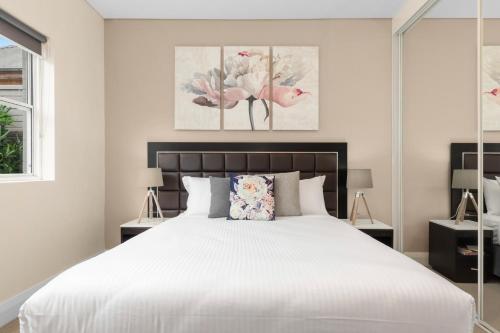 een slaapkamer met een groot wit bed met bloemen bij The Banq Apartments by Urban Rest in Sydney