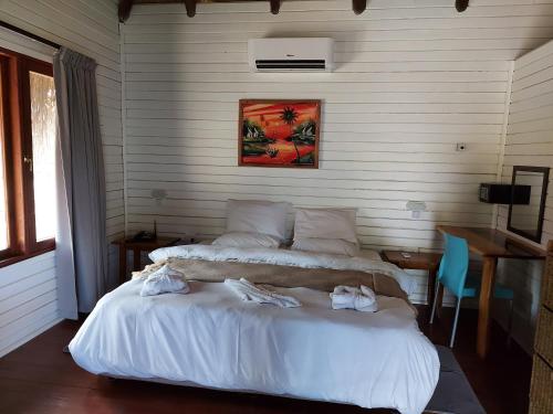 a bedroom with two beds and a table with a desk at East Africa Safaris in Chizavane