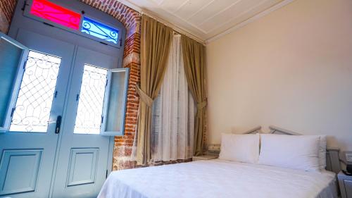 a bedroom with a bed and a blue door and a window at Cunda Ömer Ağa Konağı in Cunda