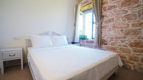 a white bed in a room with a brick wall at Cunda Ömer Ağa Konağı in Cunda