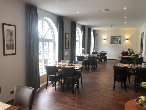 a dining room with tables and chairs and windows at WH Hotels Papenburg Zentrum in Papenburg