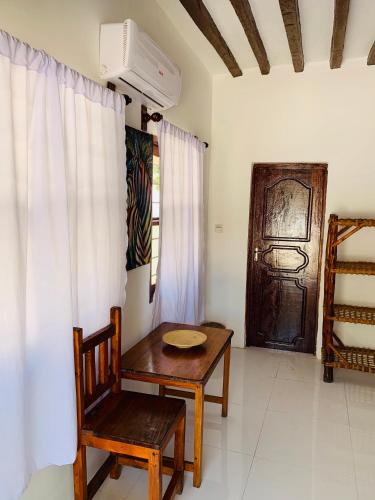 a room with a table and a chair and a door at Zava Nungwi in Nungwi