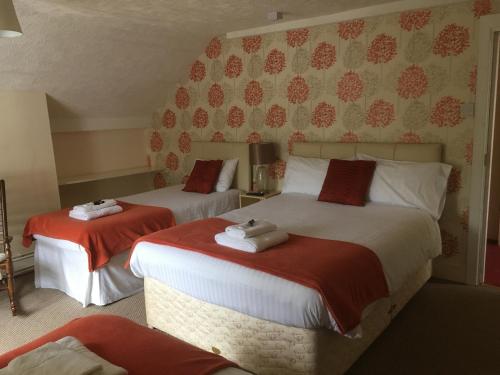 1 dormitorio con 2 camas con sábanas rojas y blancas en The New Inn en Oswestry