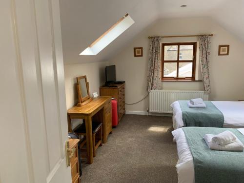a bedroom with two beds and a desk and a window at Fox and Hounds Cottage, Starbotton in Starbotton