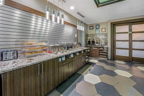a large kitchen with wooden cabinets and a checkered floor at La Quinta Inn & Suite Kingwood Houston IAH Airport 53200 in Kingwood