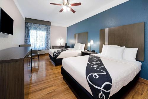 a hotel room with two beds and a flat screen tv at La Quinta Inn & Suite Kingwood Houston IAH Airport 53200 in Kingwood