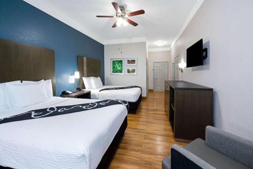 a hotel room with two beds and a ceiling fan at La Quinta Inn & Suite Kingwood Houston IAH Airport 53200 in Kingwood