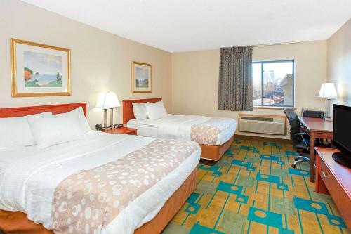 a hotel room with two beds and a flat screen tv at La Quinta Inn by Wyndham Milwaukee Airport / Oak Creek in Oak Creek