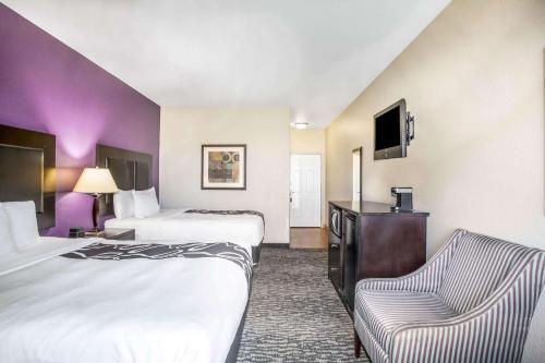 a hotel room with two beds and a chair at La Quinta by Wyndham Kyle - Austin South in Kyle