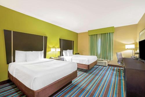 a hotel room with two beds and a television at La Quinta by Wyndham Muskogee in Muskogee