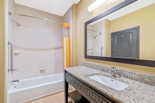 a bathroom with a sink and a tub and a mirror at La Quinta by Wyndham Muskogee in Muskogee