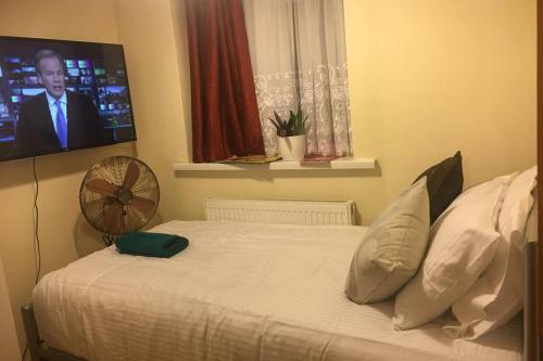 a bedroom with a bed with a tv on the wall at F3 Cosy Single Room (Sandycroft Guest House) in London
