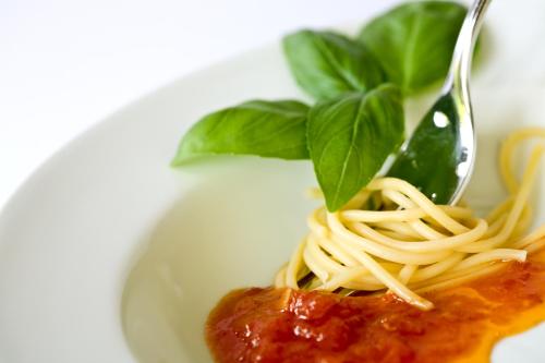 a plate of spaghetti with a fork and basil on it at Lindner Hotel Frankfurt Hochst, part of JdV by Hyatt in Frankfurt/Main