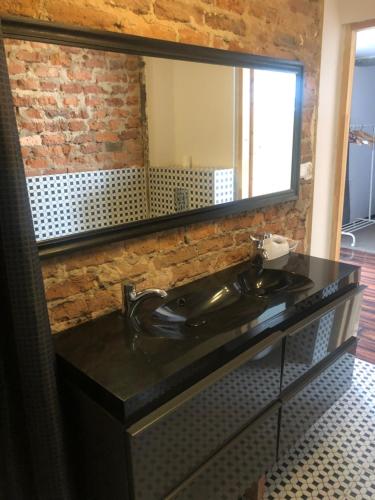baño con lavabo negro y espejo en Flores Apartament, en Katowice