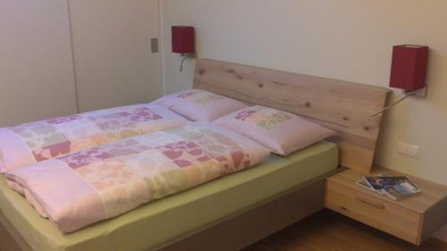a bedroom with a bed with a wooden head board at viaDolceVita - Grüne Gästewohnung in Lana