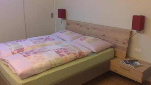 ein Schlafzimmer mit einem Bett mit einem Kopfteil aus Holz in der Unterkunft viaDolceVita - Grüne Gästewohnung in Lana