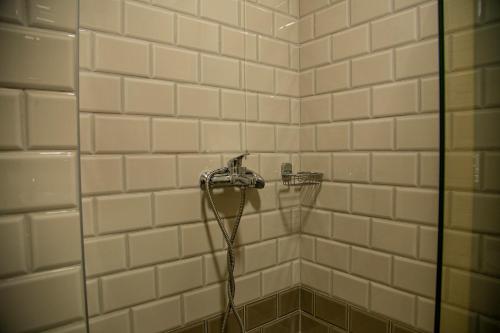 a shower with a hose in a white tiled bathroom at Dafni Plus Hotel in Leptokaria